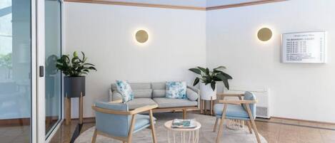 A modern waiting area with a sofa, chairs, a small table, and potted plants.