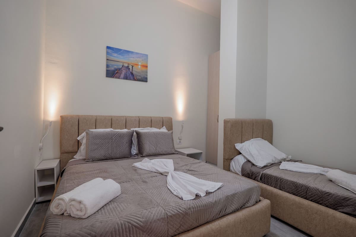 A hotel room with a large bed, a smaller bed, and a painting on the wall.