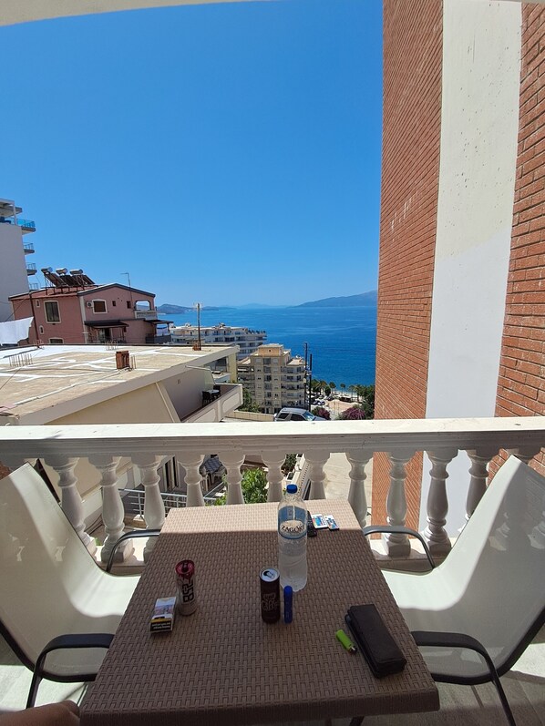 A balcony with a table, a bottle of water, a can of soda, and a smartphone. - Esel Apartments (Sarandë)