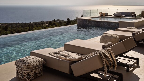 Une piscine à débordement avec des chaises longues et une vue sur la mer.