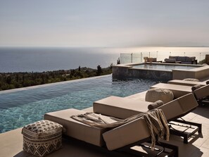 A infinity pool with lounge chairs and a view of the sea. - Elpida Luxury Villa, with Infinity Pool & Jacuzzi (VMHX+2PP Elation, Greece)