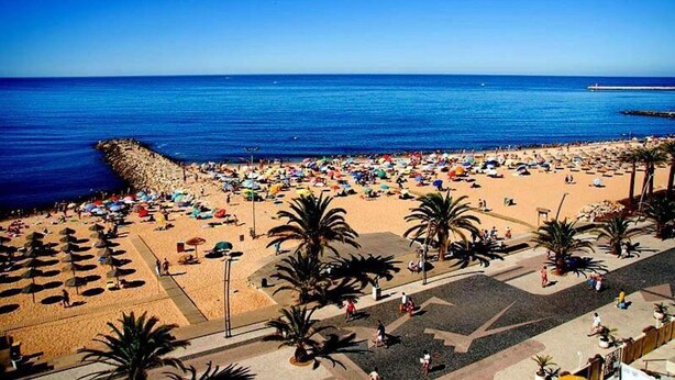 Une plage avec des parasols et des gens.