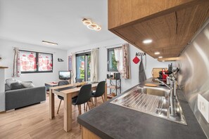 A modern kitchen with a wooden countertop, stainless steel sink, and a dining area with a table and chairs.
