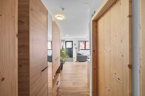 A modern interior with wooden flooring, a hallway leading to a living area with a sofa and a plant.