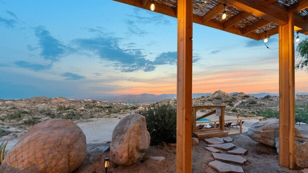 Una pergola in legno con vista su un paesaggio desertico al tramonto.