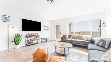 Ein modernes Wohnzimmer mit einer Couch, einem Couchtisch und einem an der Wand montierten Flachbildfernseher.
