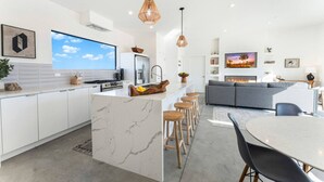 A modern kitchen with a large island, bar stools, and a dining table. - Sun Gold | Secluded> Breathtaking Sunsets> Unique (Joshua Tree)