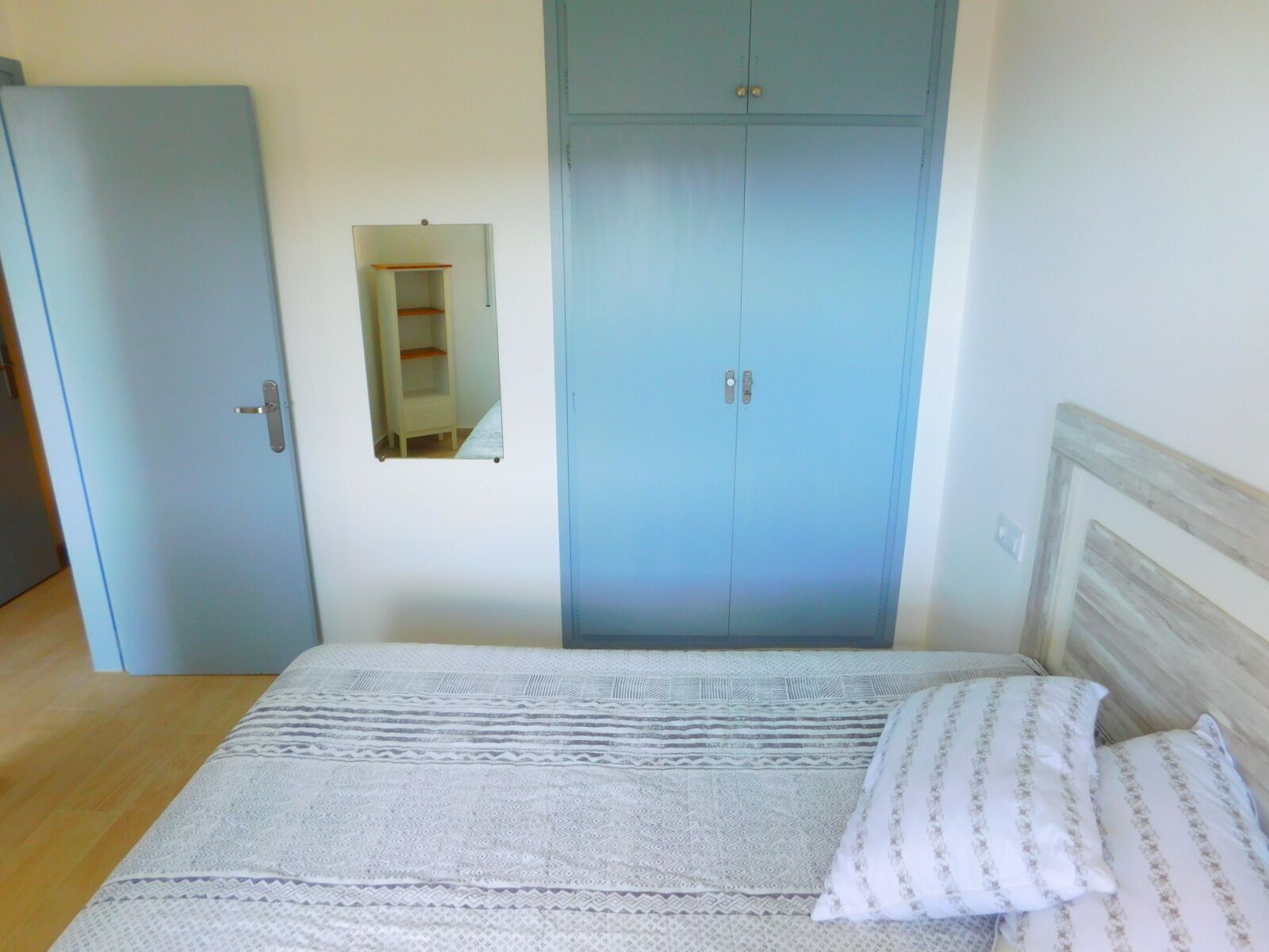 Ein Schlafzimmer mit einem Bett, einem Kleiderschrank und einem Spiegel.