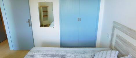 Ein Schlafzimmer mit einem Bett, einem Kleiderschrank und einem Spiegel.