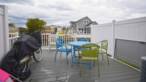 A covered outdoor patio with a table and chairs, a bicycle, and a trash can.