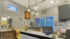 Een receptiegedeelte met een houten wand, een grote spiegel, een bureau met een computer en een koffieapparaat.