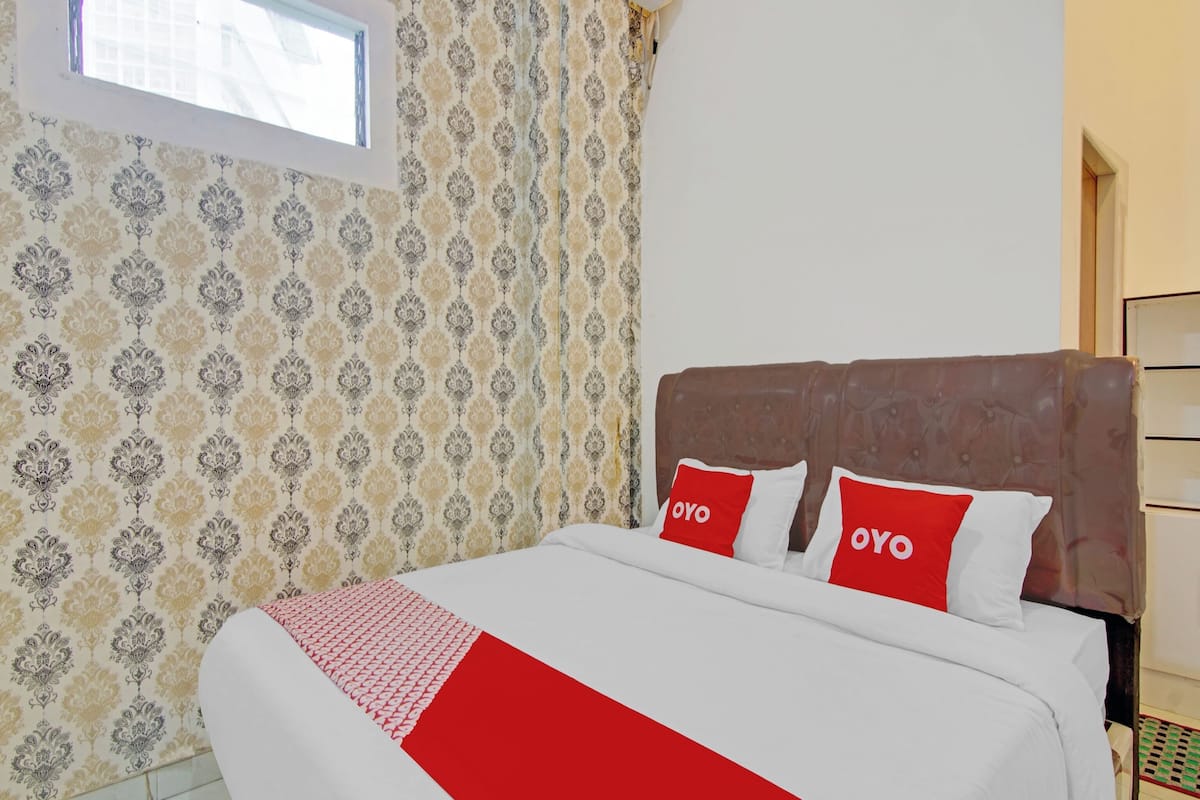 A hotel room with a large bed, patterned wallpaper, and a window with a view.