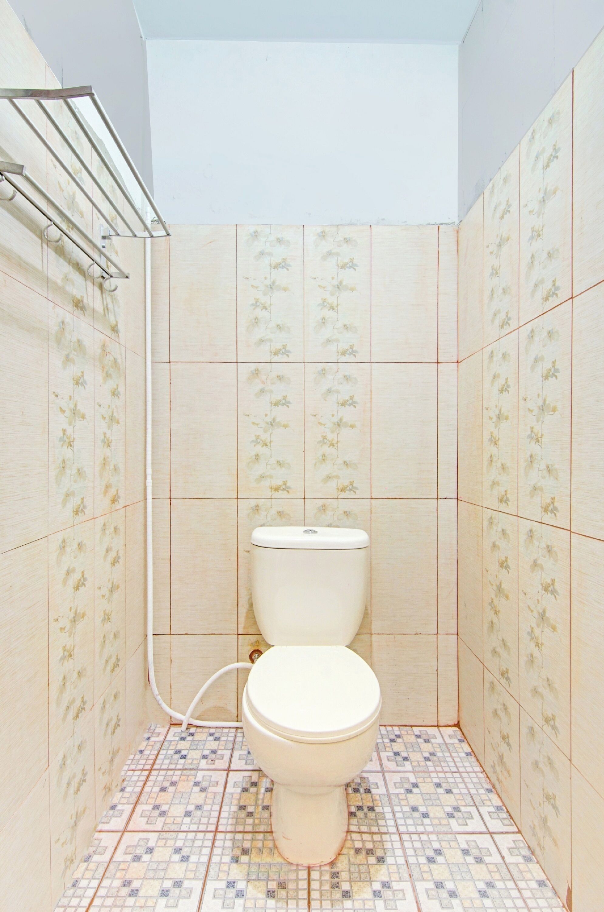 A bathroom with a toilet, tiled walls, and a tiled floor.