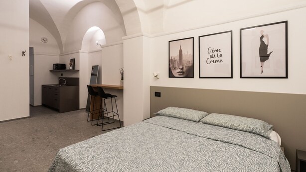 Un dormitorio con una cama, un escritorio y una silla. Hay tres cuadros enmarcados en la pared.