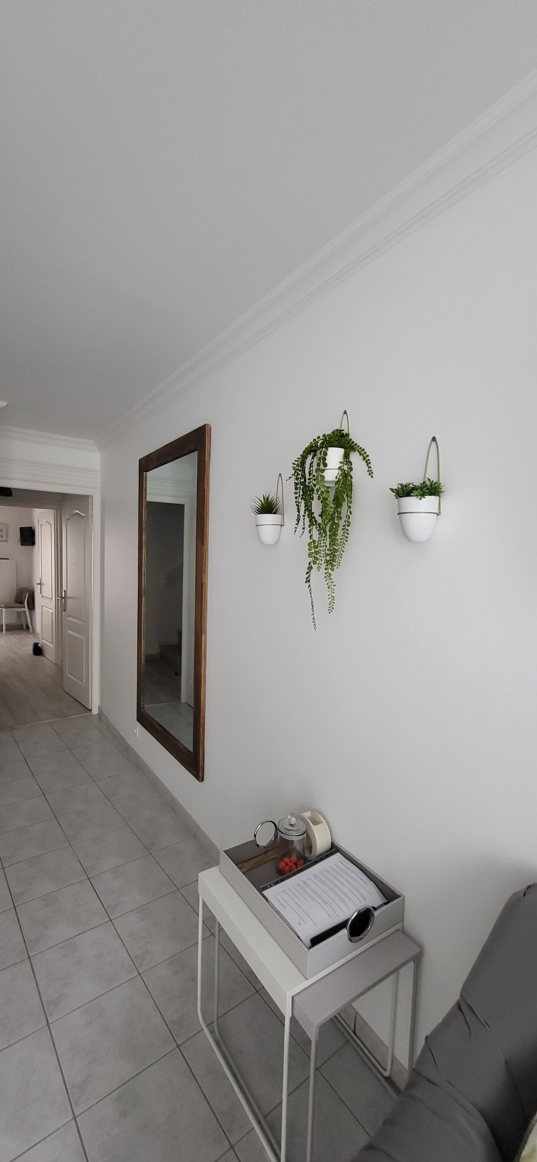 A modern room with a large mirror, a desk with a computer, and two wall-mounted planters.