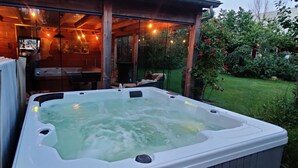 A hot tub in a covered outdoor area with wooden walls and string lights.