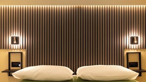 A hotel room with a bed, two bedside tables, and a wall-mounted light fixture. - OlbiaLoft (Olbia)