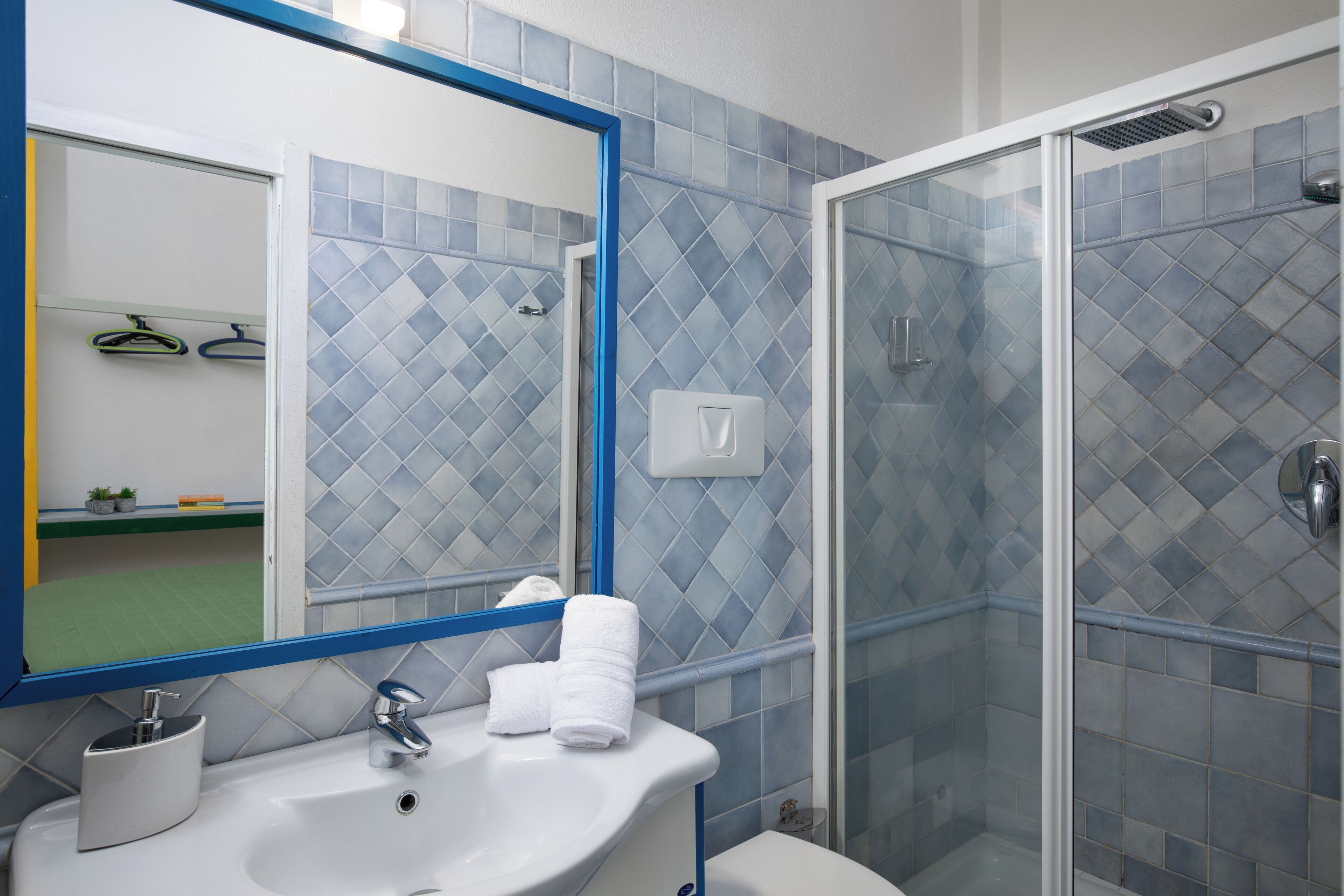 A bathroom with a sink, mirror, and shower.