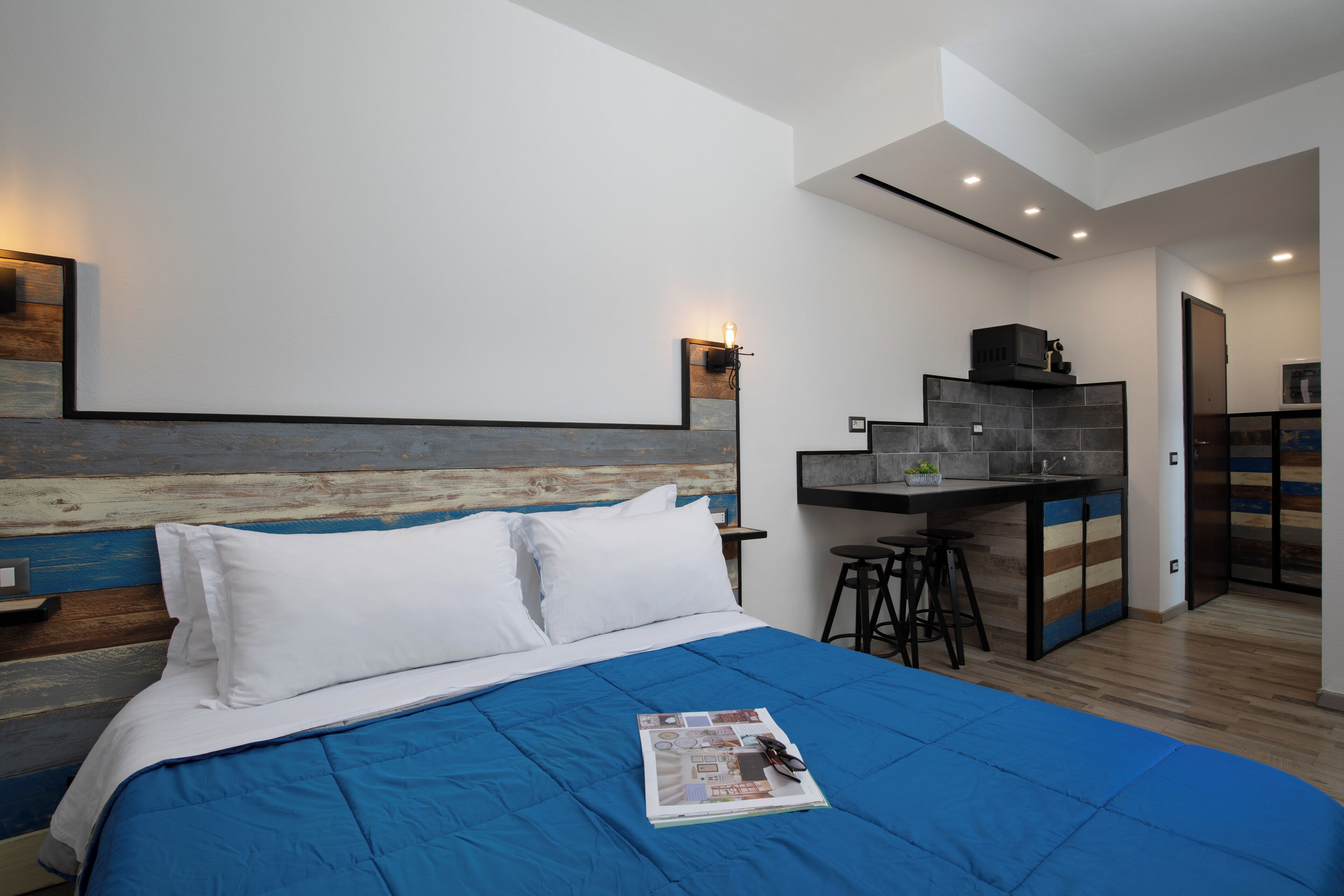 Une chambre moderne avec un grand lit, un bureau et un coin cuisine.
