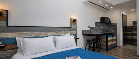 Une chambre moderne avec un grand lit, un bureau et un coin cuisine.