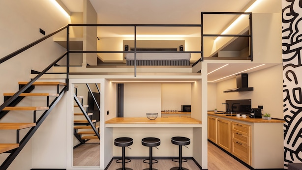A modern kitchen with a central island, wooden flooring, and a staircase leading to an upper level. - OlbiaLoft (Olbia)