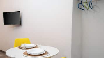 A dining area with a round table, yellow chairs, and a flat-screen TV mounted on the wall.
