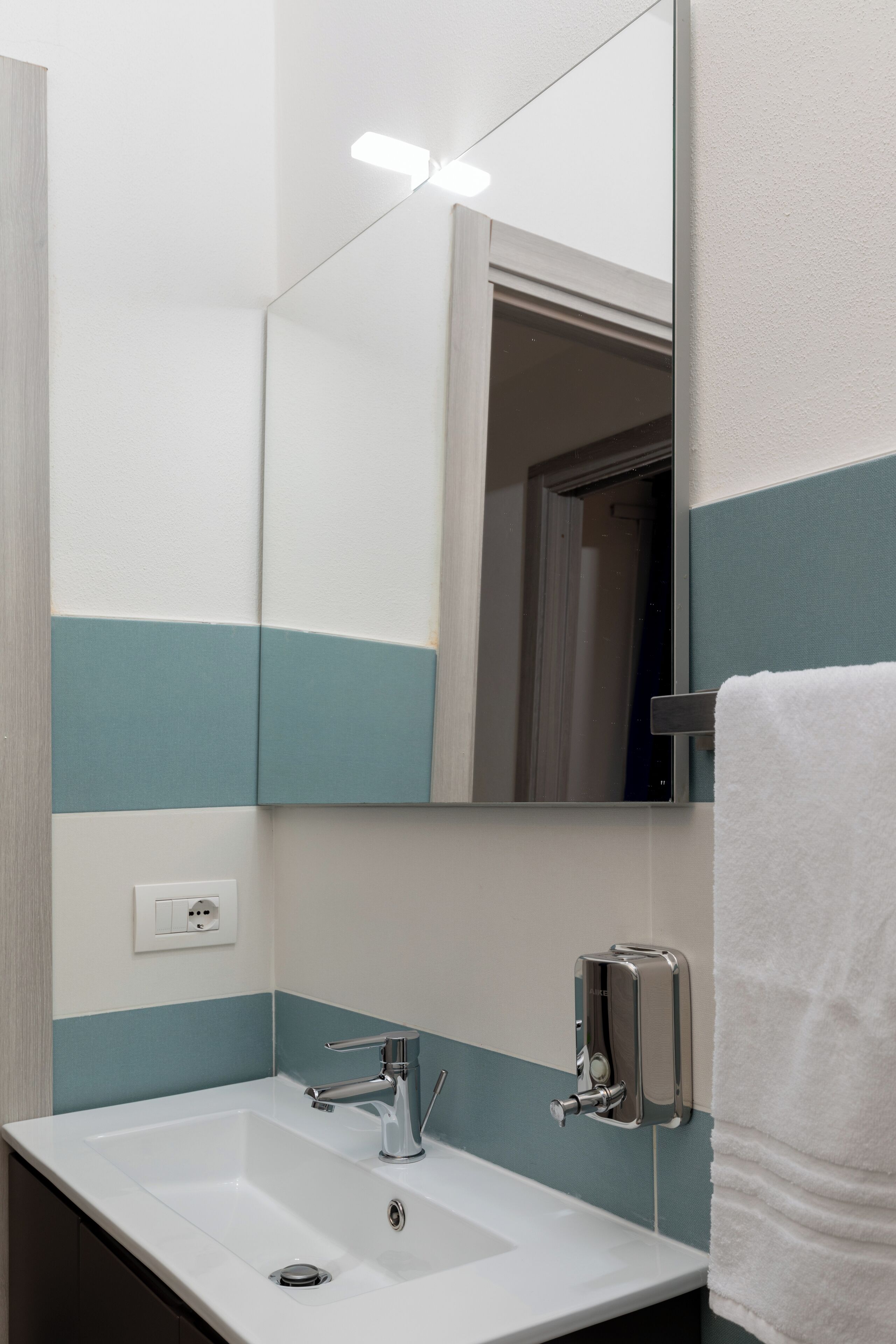 A bathroom with a white sink, chrome faucet, and a mirror.