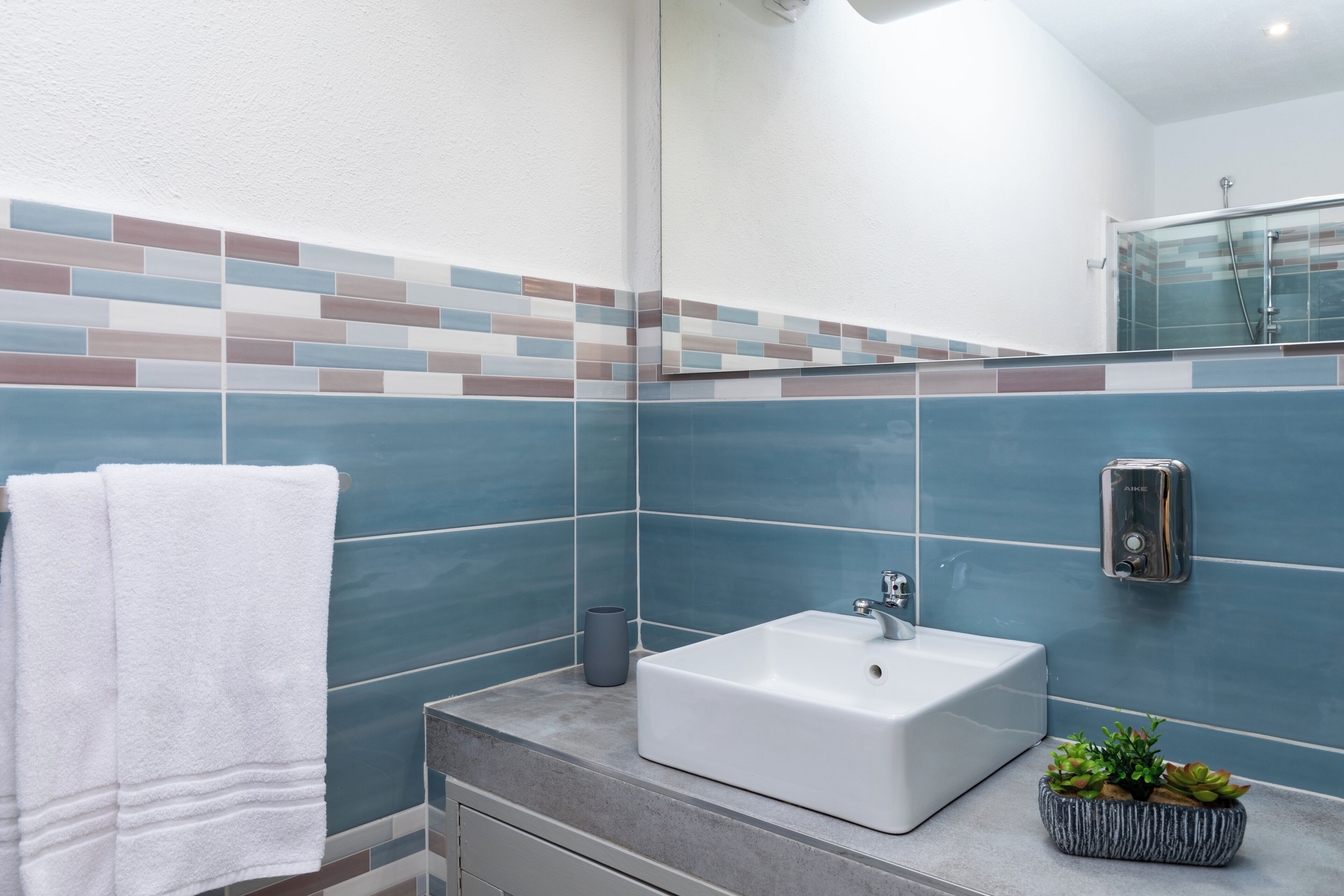 A bathroom with a white sink, a mirror, and a tiled backsplash.