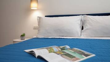 A neatly made bed with a blue bedspread, white pillows, and a magazine on the bed.