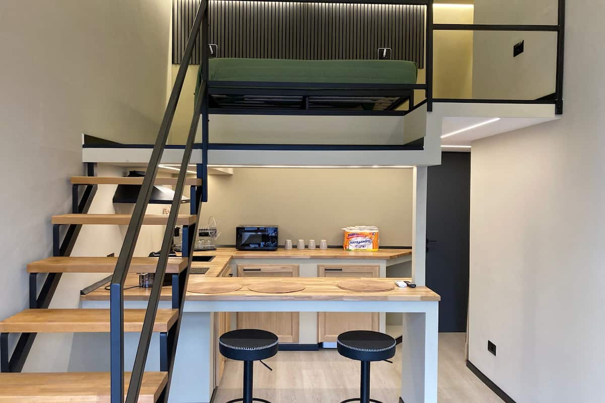 Ein modernes Interieur mit Treppe, einer Küchenzeile und einem Essbereich mit Hockern.