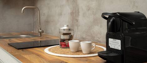 Eine Küche mit Kaffeemaschine, zwei weißen Tassen und einem Glasbehälter auf einer Holz Arbeitsplatte.