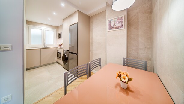 A modern kitchen with stainless steel appliances, a dining table with chairs, and a pendant light. - Apartamento muy Coqueto a 5 Min, Pabellon Principe Felipe (Zaragoza)