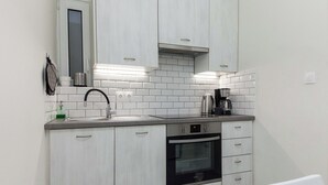 Une cuisine moderne avec des meubles blancs, un four noir et une machine à café.