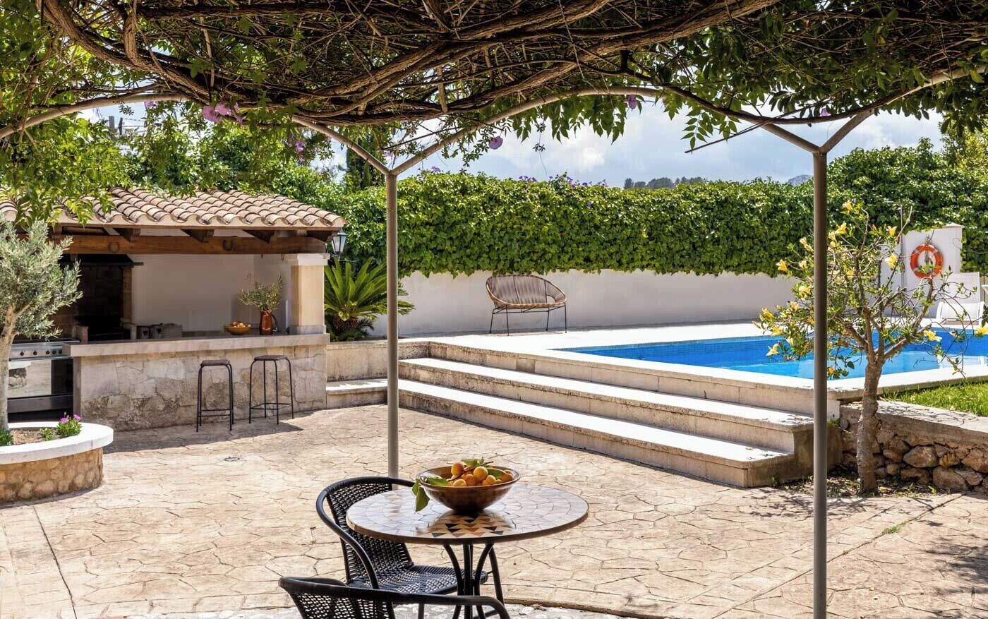 A patio with a pool, outdoor seating, and a pergola.