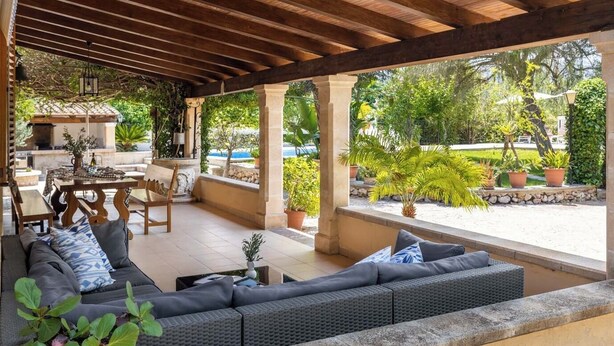 Un espace extérieur aménagé, abrité et doté d’un canapé, de chaises et d’une table.