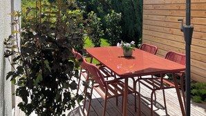 An outdoor patio with a red table and chairs, a white umbrella, and a potted plant. - Charmantes Design-appartement für 2 Personen in Utting am Ammersee (Utting am Ammersee)