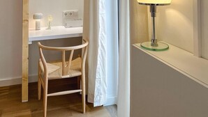 A modern bathroom with a wooden chair, a white vanity, and a floor lamp. - Charmantes Design-appartement für 2 Personen in Utting am Ammersee (Utting am Ammersee)