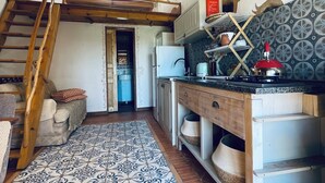 A rustic kitchen with a wooden staircase, a patterned floor, and a kitchen counter with various items. - Destination for Couple, Surfers, Hikers, and Nature Lovers! (Carrapateira)