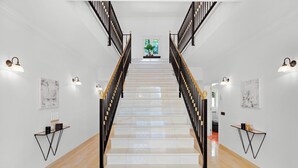 A staircase with black railings and wall-mounted light fixtures.