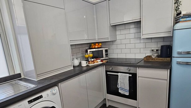 A compact kitchen with a washing machine, a microwave, and a small oven.