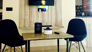 Un comedor moderno con un televisor de pantalla plana montado en un panel de madera, una mesa con dos sillas y un control remoto sobre la mesa.