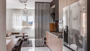 A modern kitchen with a large refrigerator, wooden cabinets, and a view of the outdoors. - Summer Dream Apartment with garden, patio and pool (Sv. Filip i Jakov)