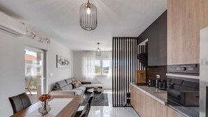 A modern kitchen with a built-in oven and a dining area with a wooden table and chairs. - Summer Dream Apartment with garden, patio and pool (Sv. Filip i Jakov)