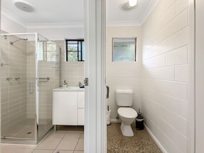A bathroom with a glass shower enclosure, a white sink, and a toilet. - Nerita Nook (Nelly Bay)