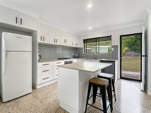 Cozinha moderna com armários brancos, uma ilha central e uma janela grande.