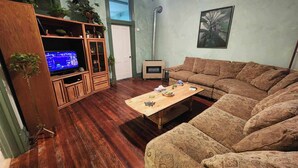 Una sala de estar con un mueble de madera para centro de entretenimiento, un sofá, una mesa de centro y una chimenea.