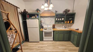 Una cocina con gabinetes verdes, un refrigerador blanco, una estufa y una encimera de madera.