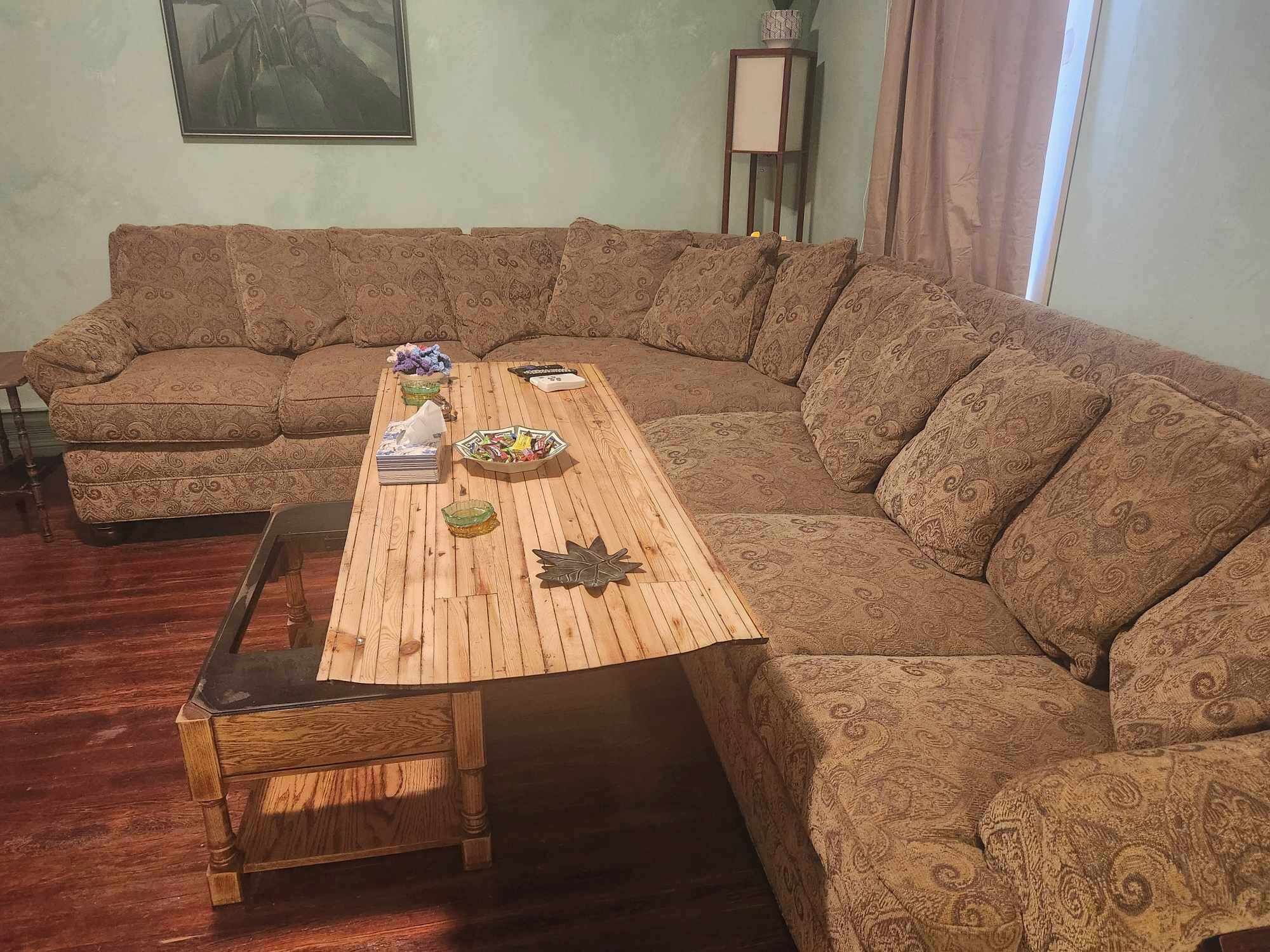 A living room with a large L-shaped sectional sofa, a wooden coffee table, and a small side table.