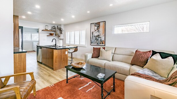 Un salon moderne comprenant un canapé, une table basse et un coin cuisine avec une table à manger et un bar.