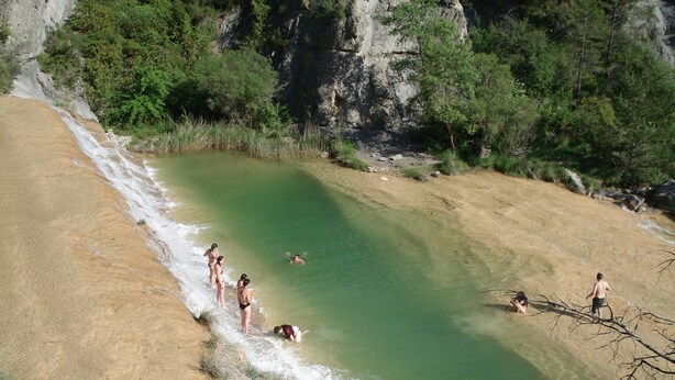 Una piscina natural rodeada de terreno rocoso y vegetación.